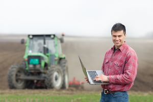 man-laptop-tractor-field